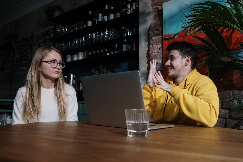 A man using sign language to communicate with a woman in a cozy cafe setting.